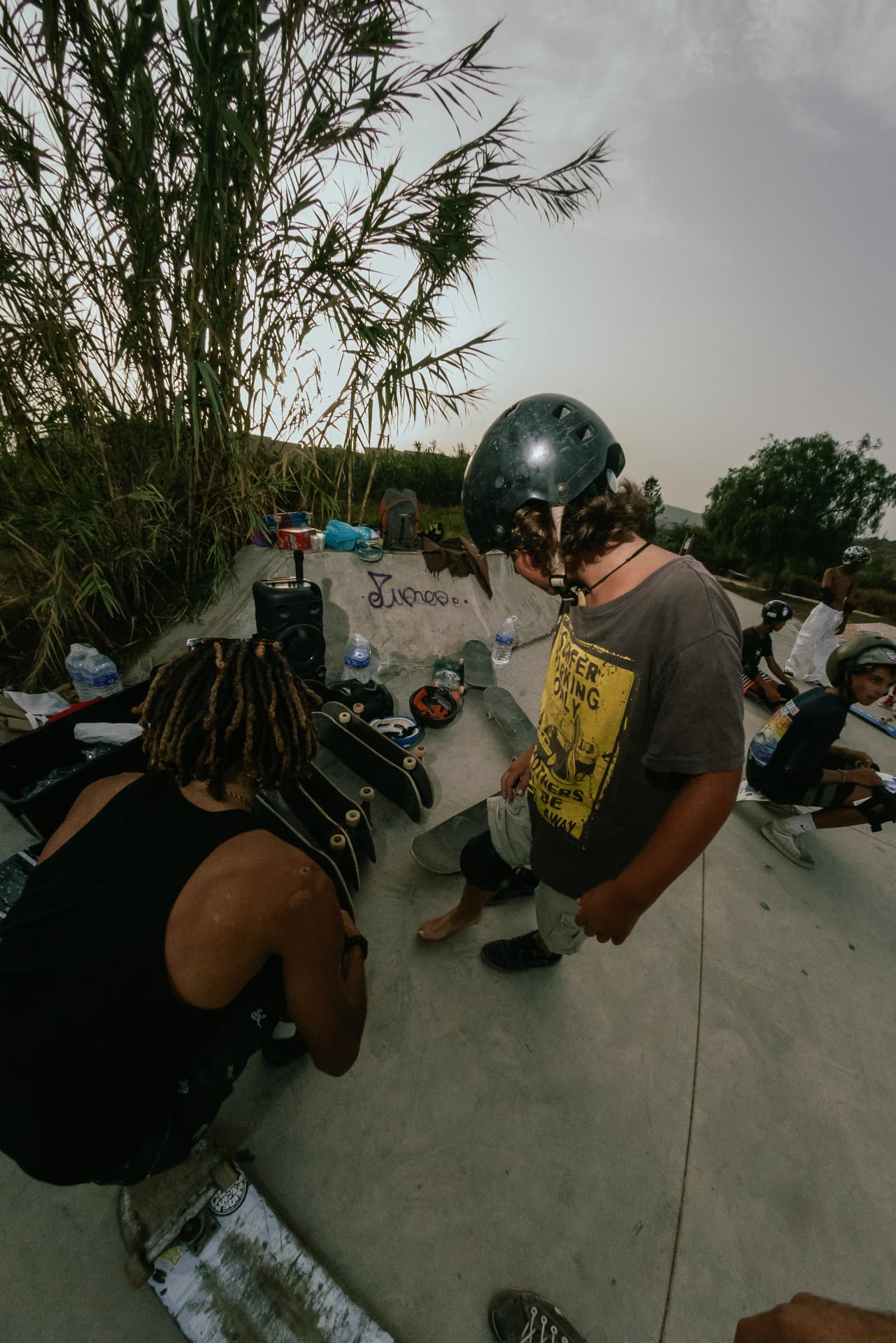 Coach checking helmets and boards with young riders before a session at sunset
