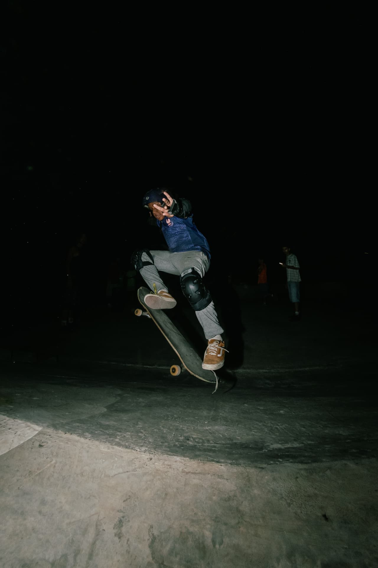 Skater mid-trick shielding the camera flash during a late session