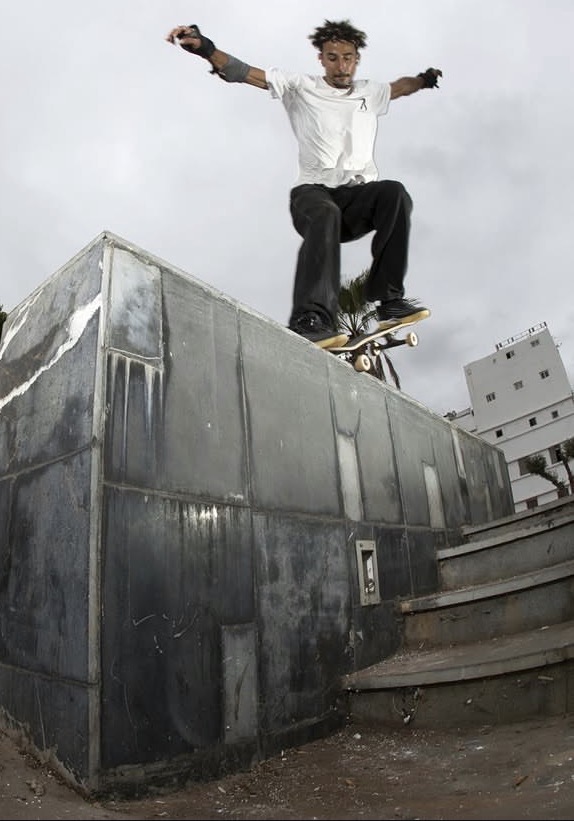 Akram Moundo, founder and coach of Casa Skate Club, balancing on his skateboard along the edge of a high concrete wall