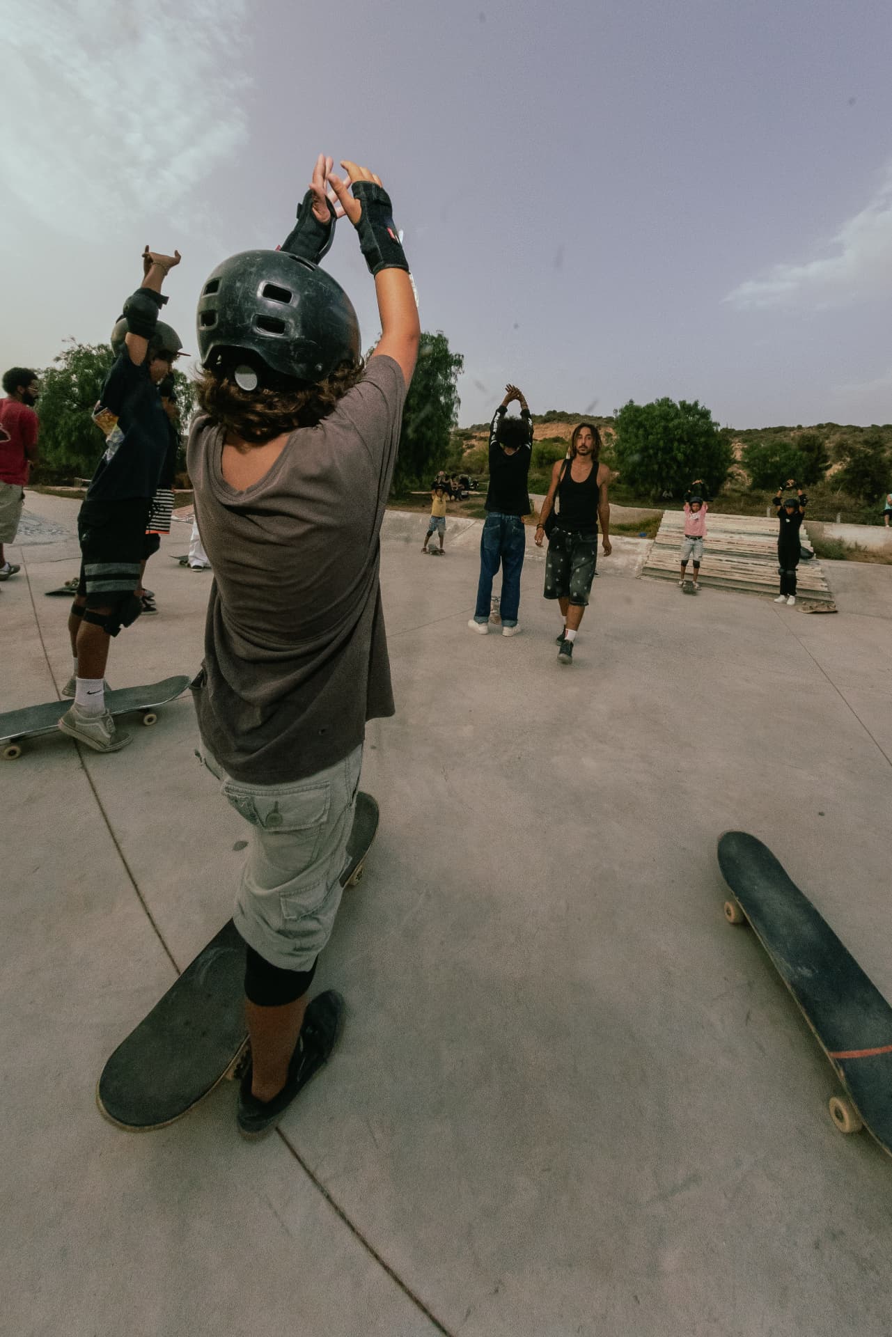 Group of young skaters warming up with arms raised at the start of a Casa Skate Club session
