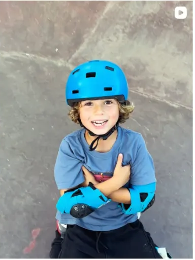 Smiling young skater wearing a blue helmet and pads