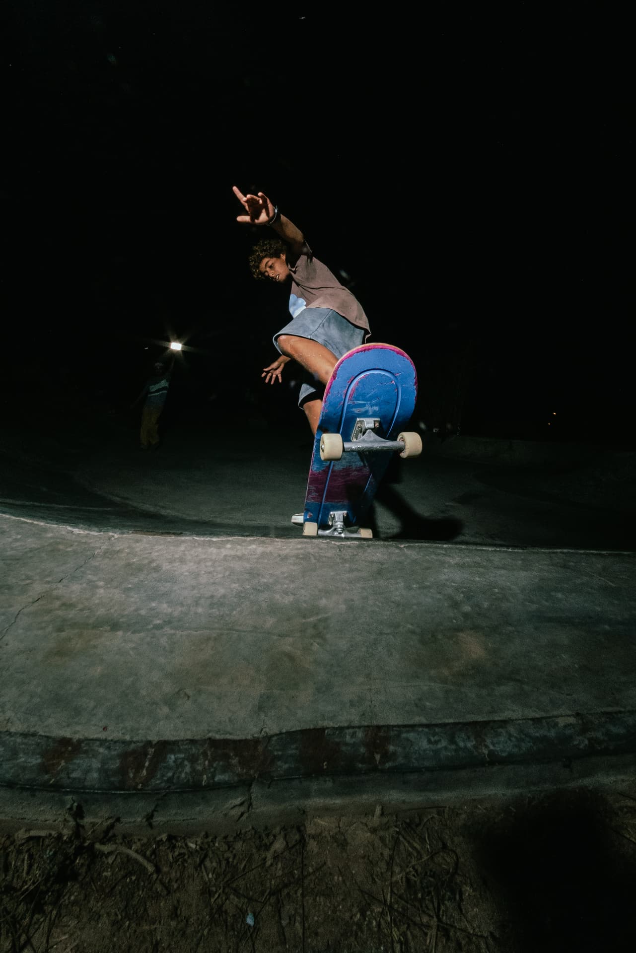 Skater carving the coping of the bowl during a night session